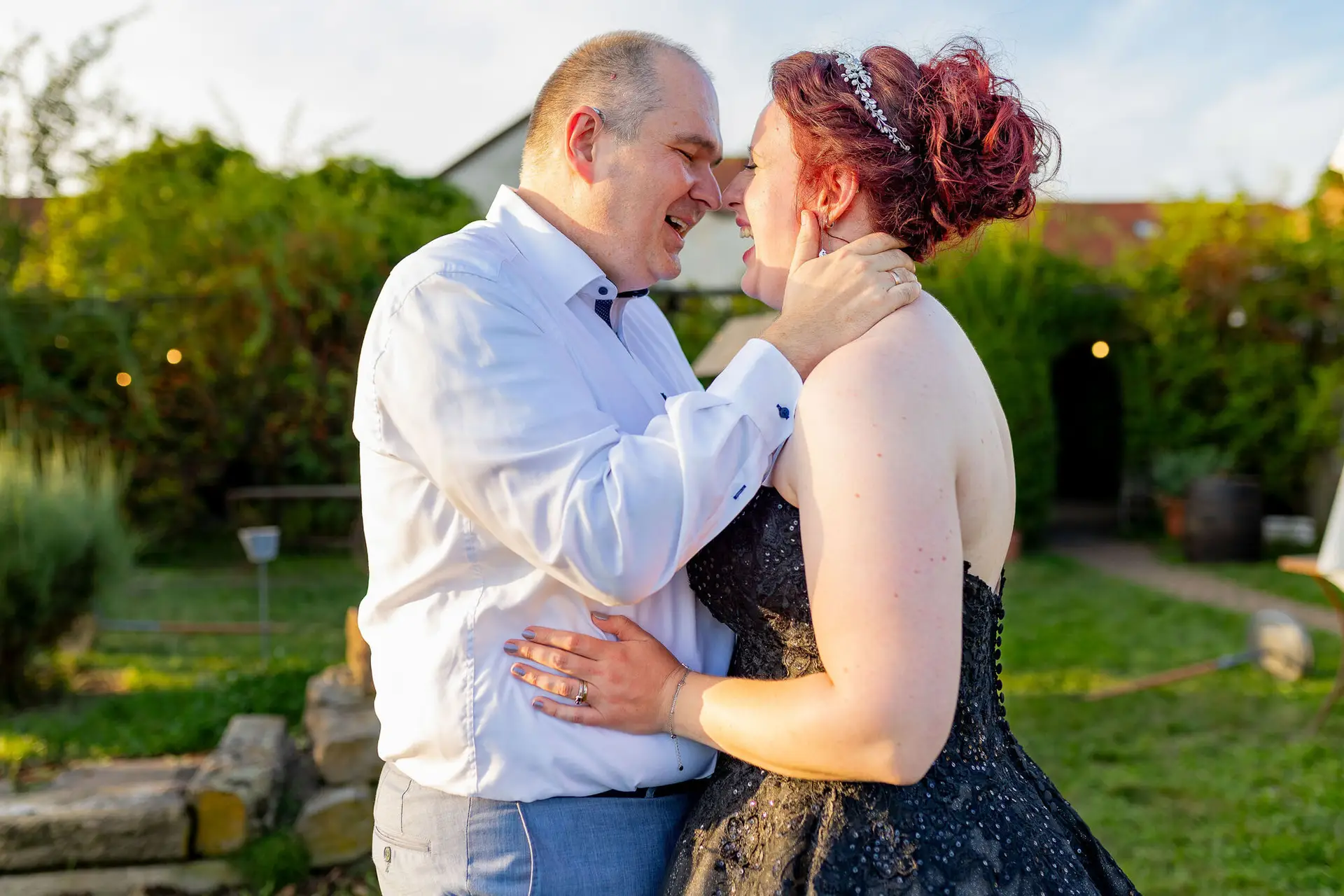 Brautpaar Stirn an Stirn in zärtlichem Moment im Garten bei Abendsonne