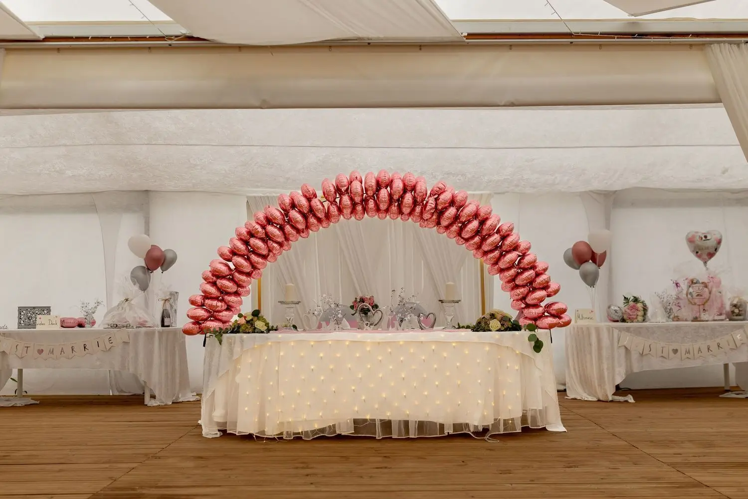 Großer rosa Luftballonbogen über dem geschmückten Brauttisch im Festzelt