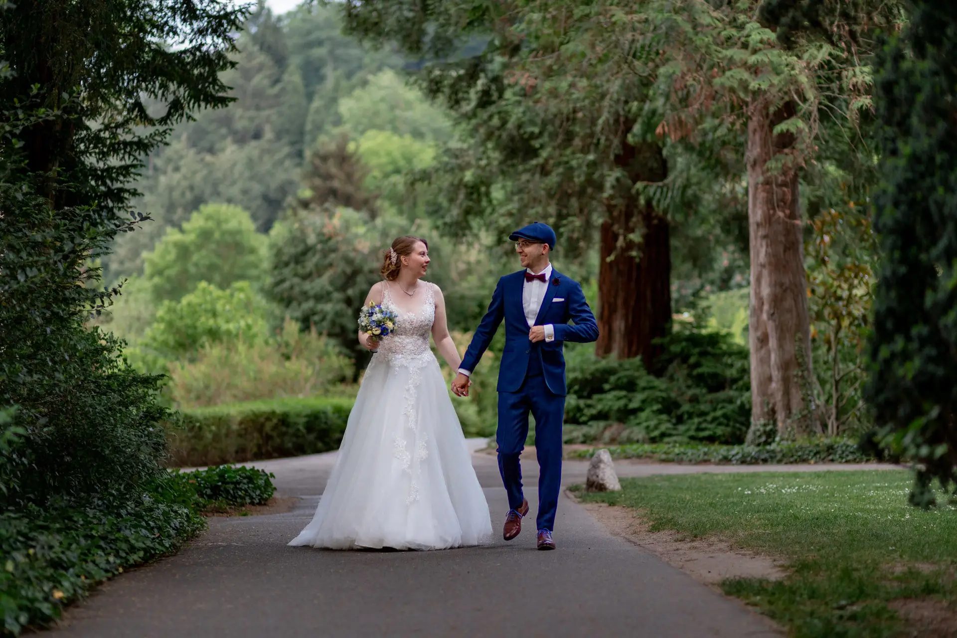 Sandra und Dominic spazieren Hand in Hand durch eine Allee im Schlosspark Weinheim