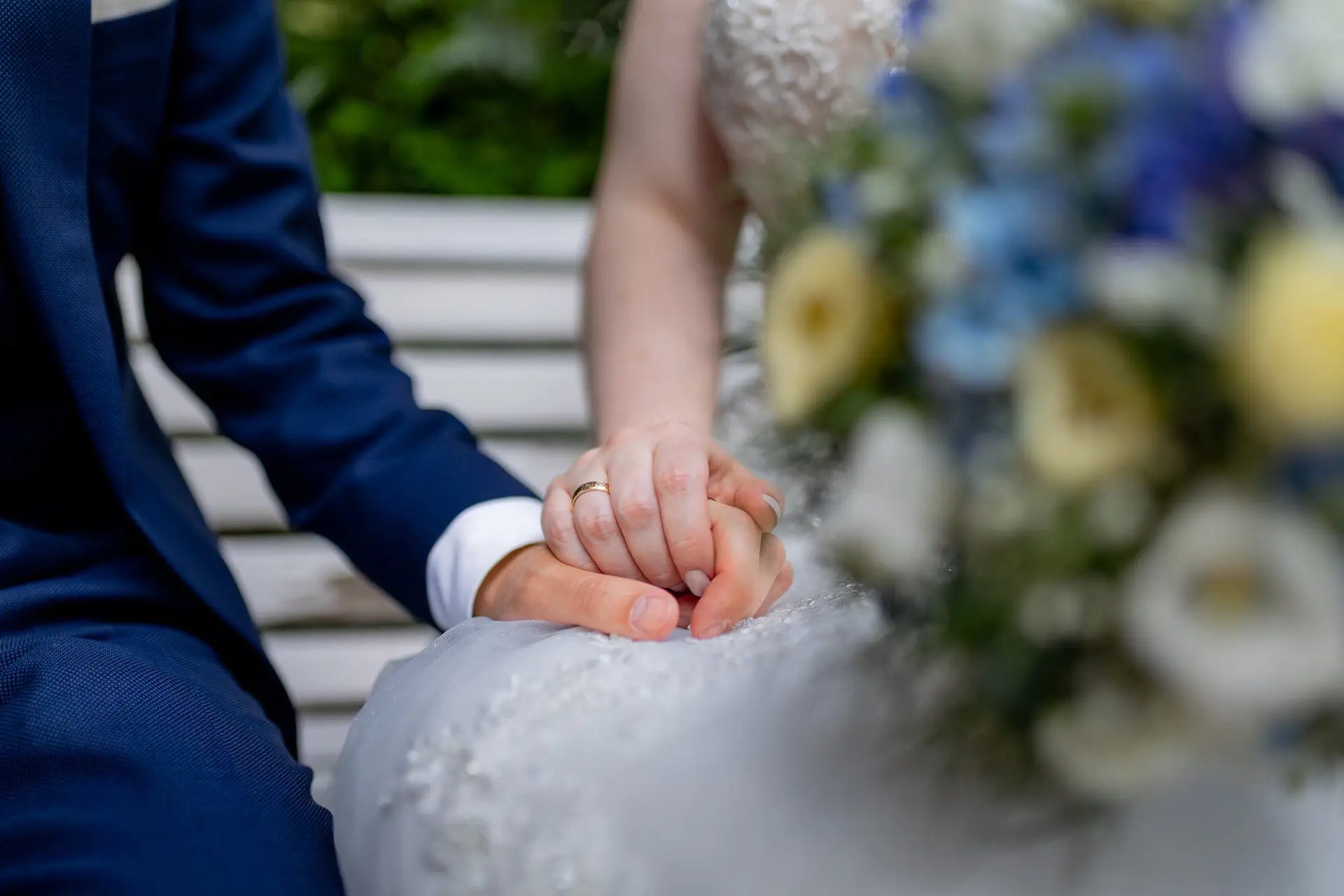 Detailaufnahme der verschränkten Hände von Sandra und Dominic mit Brautstrauß im Schlosspark Weinheim