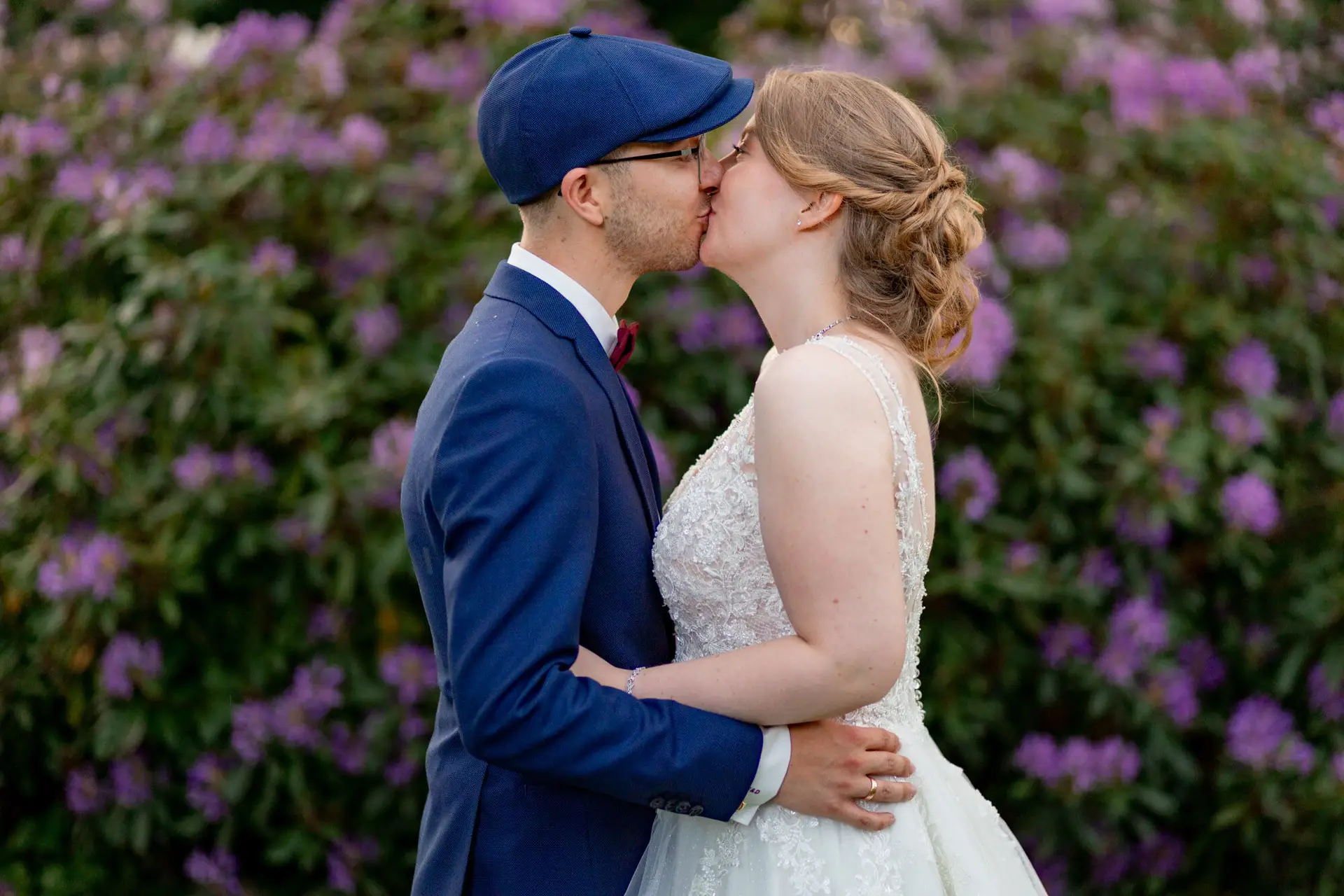 Sandra und Dominic küssen sich vor blühenden Rhododendren im Schlosspark Weinheim