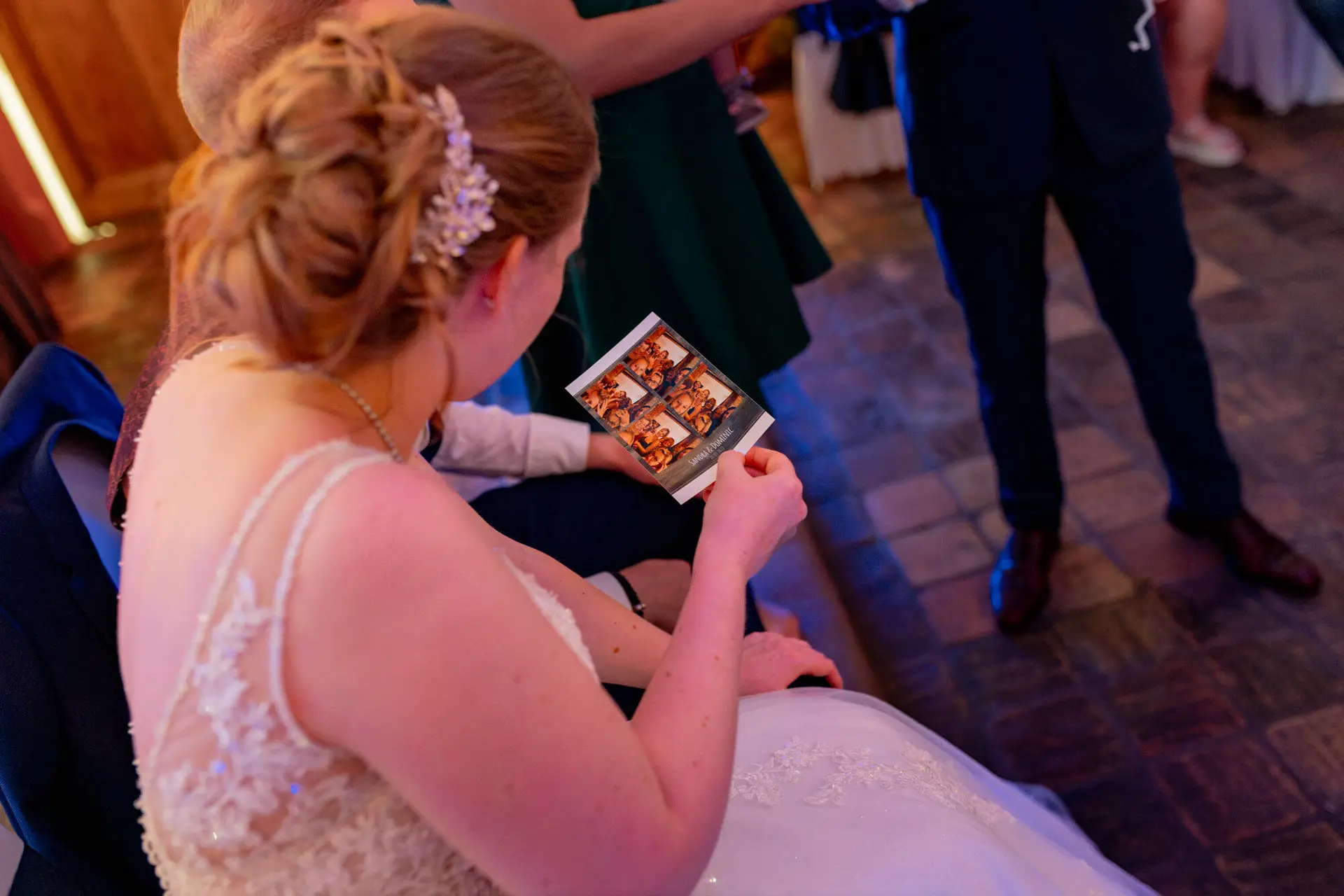 Sandra schaut sich ein Fotostreifen-Bild auf der Hochzeitsfeier in der Ulner Kapelle Weinheim an