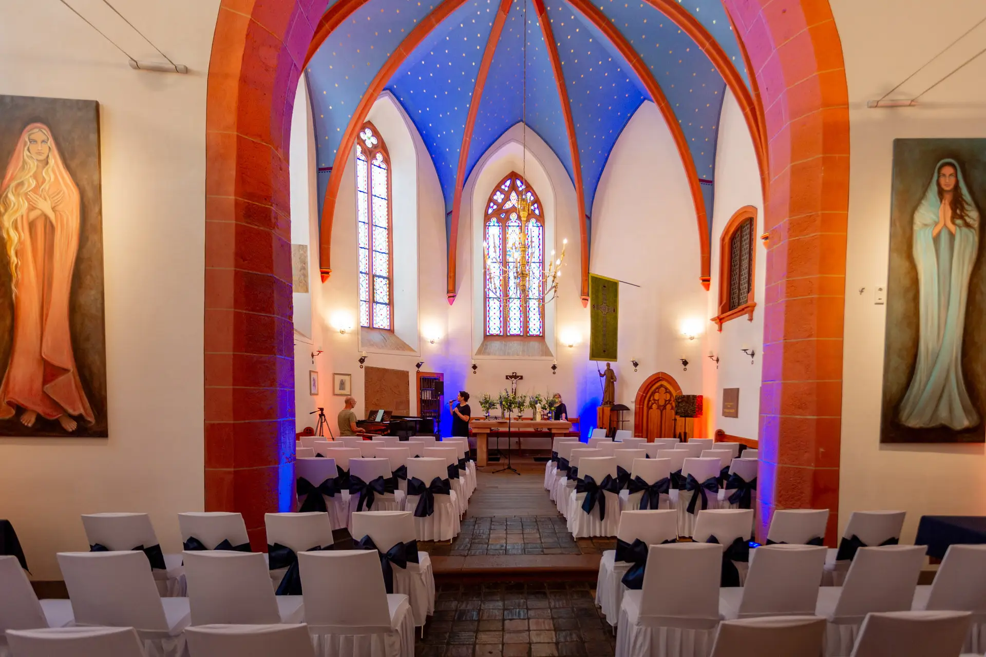 Innenraum der Ulner Kapelle Weinheim mit weißen Stühlen, blauer Beleuchtung und Blick zum Altar