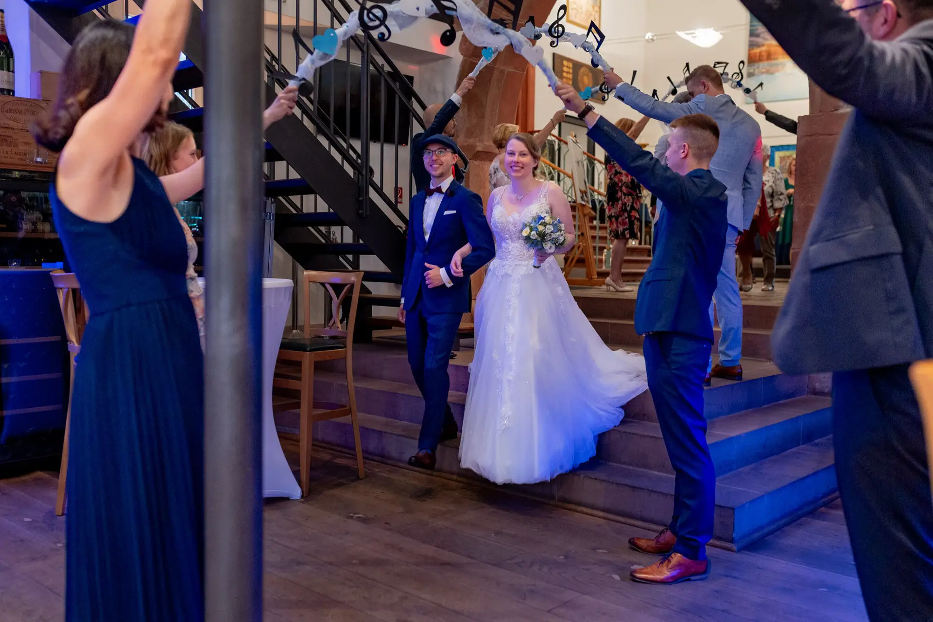 Sandra und Dominic laufen lachend durch ein Spalier der Gäste nach der Trauung in der Ulner Kapelle Weinheim