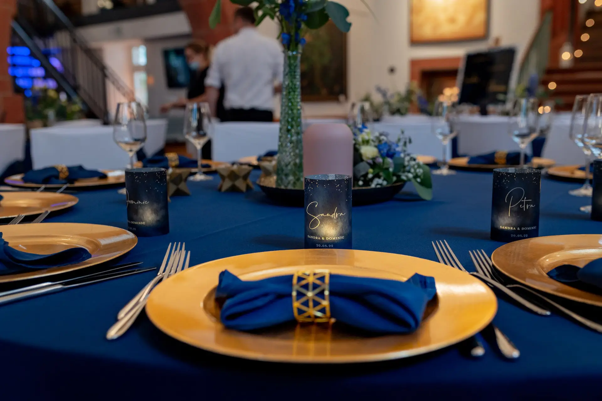 Gedeckter Tisch mit goldenen Tellern, blauen Servietten und Namenskarten in der Ulner Kapelle Weinheim