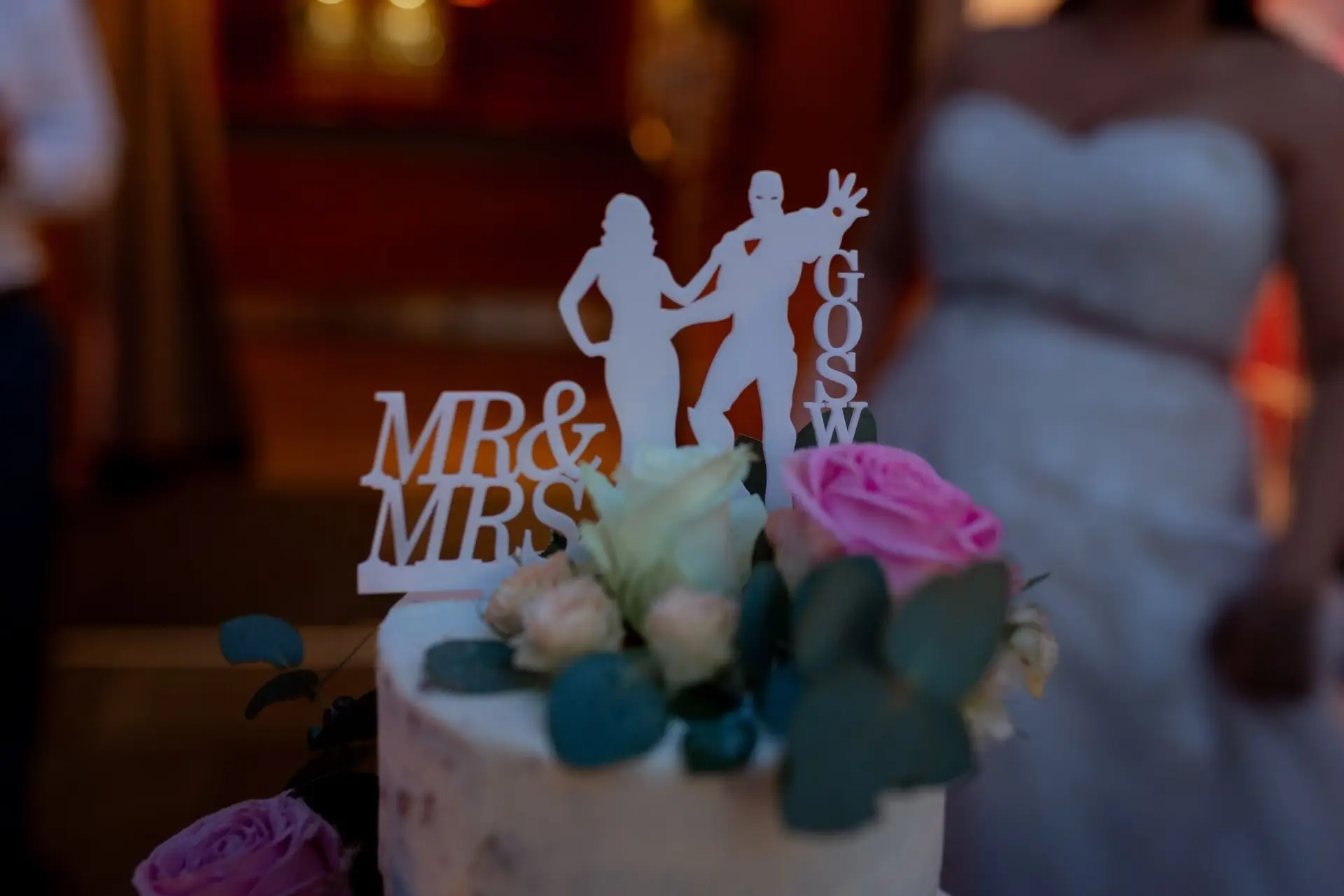 Hochzeitstorte mit "Mr. & Mrs." Silhouetten und Rosen-Dekoration beim Anschnitt