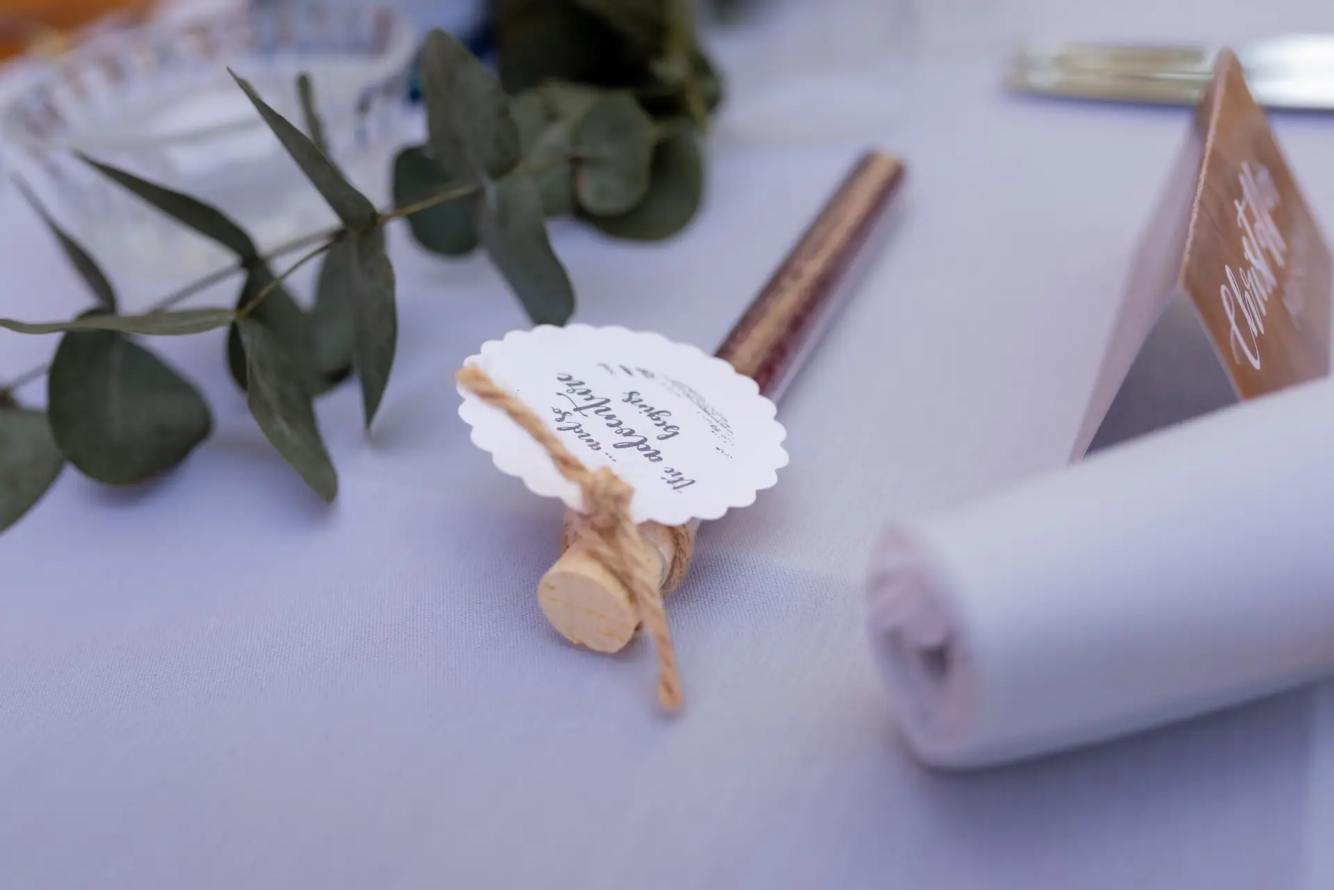 Tischdekoration mit Gastgeschenk, Namenskarte und Eukalyptuszweigen bei der Hochzeitsfeier