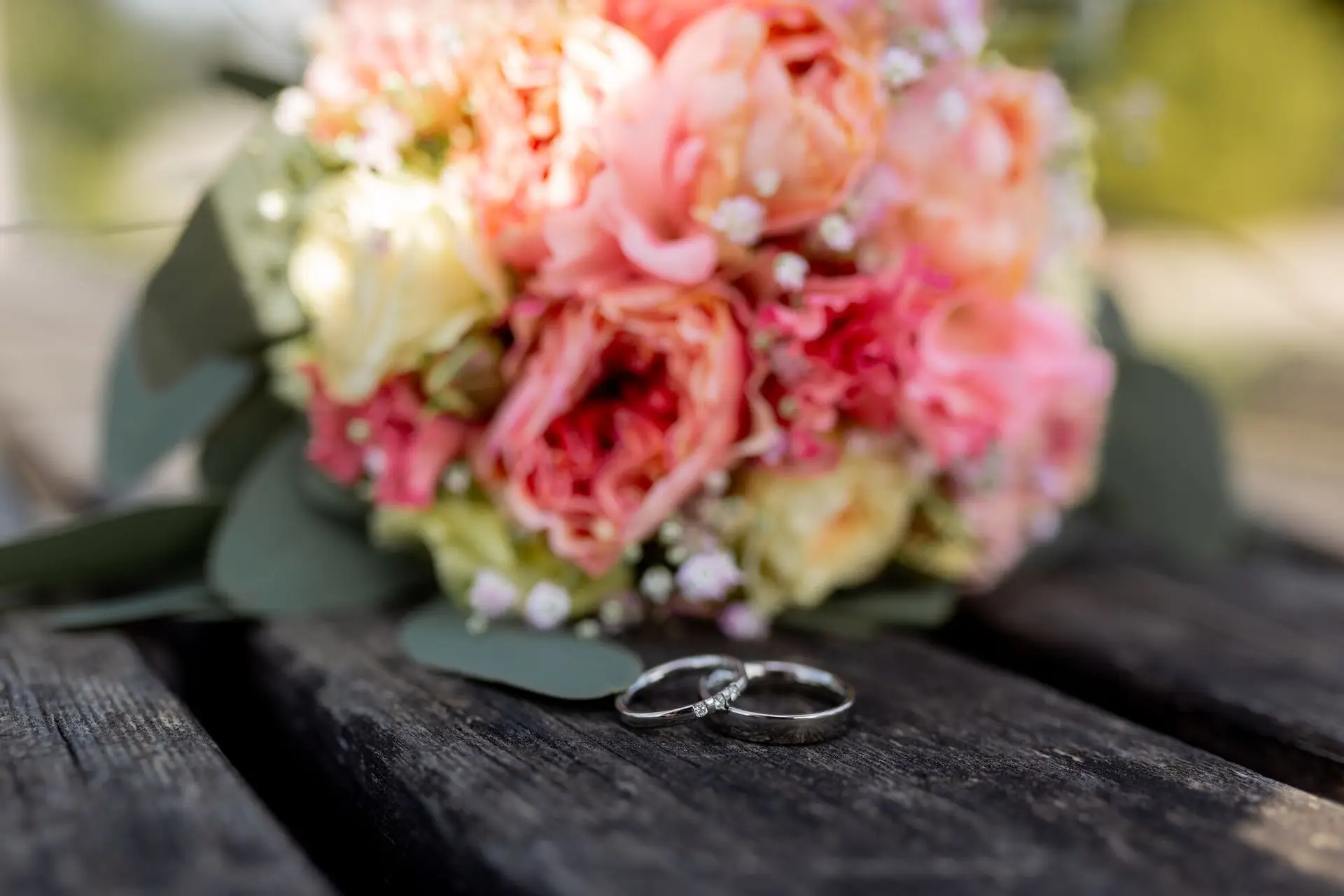 Eheringe auf verwittertem Holz neben rosa Blumenstrauß beim Brautpaarshooting Bad Dürkheim