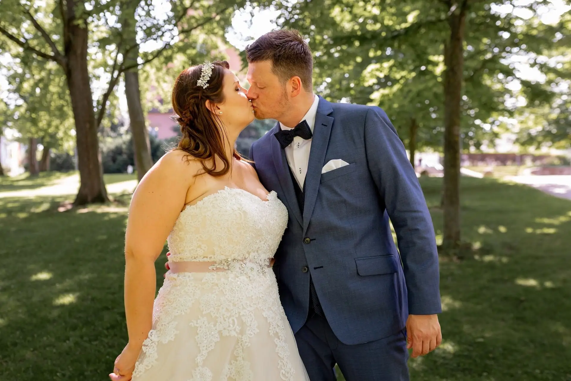 Brautpaar küsst sich im Grünen des Kurparks Bad Dürkheim, Braut im weißen Kleid