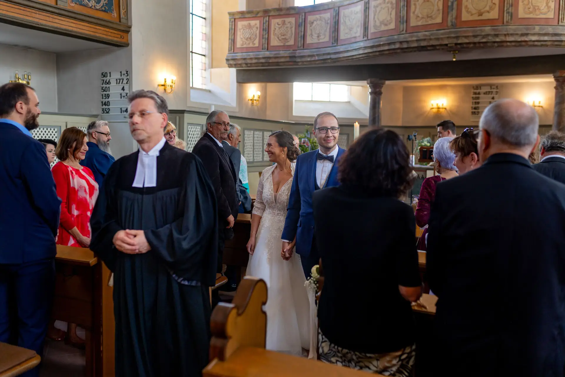 Brautpaar zieht nach der Trauung durch das Kirchenschiff mit Gewölbedecke aus, Gäste stehen Spalier