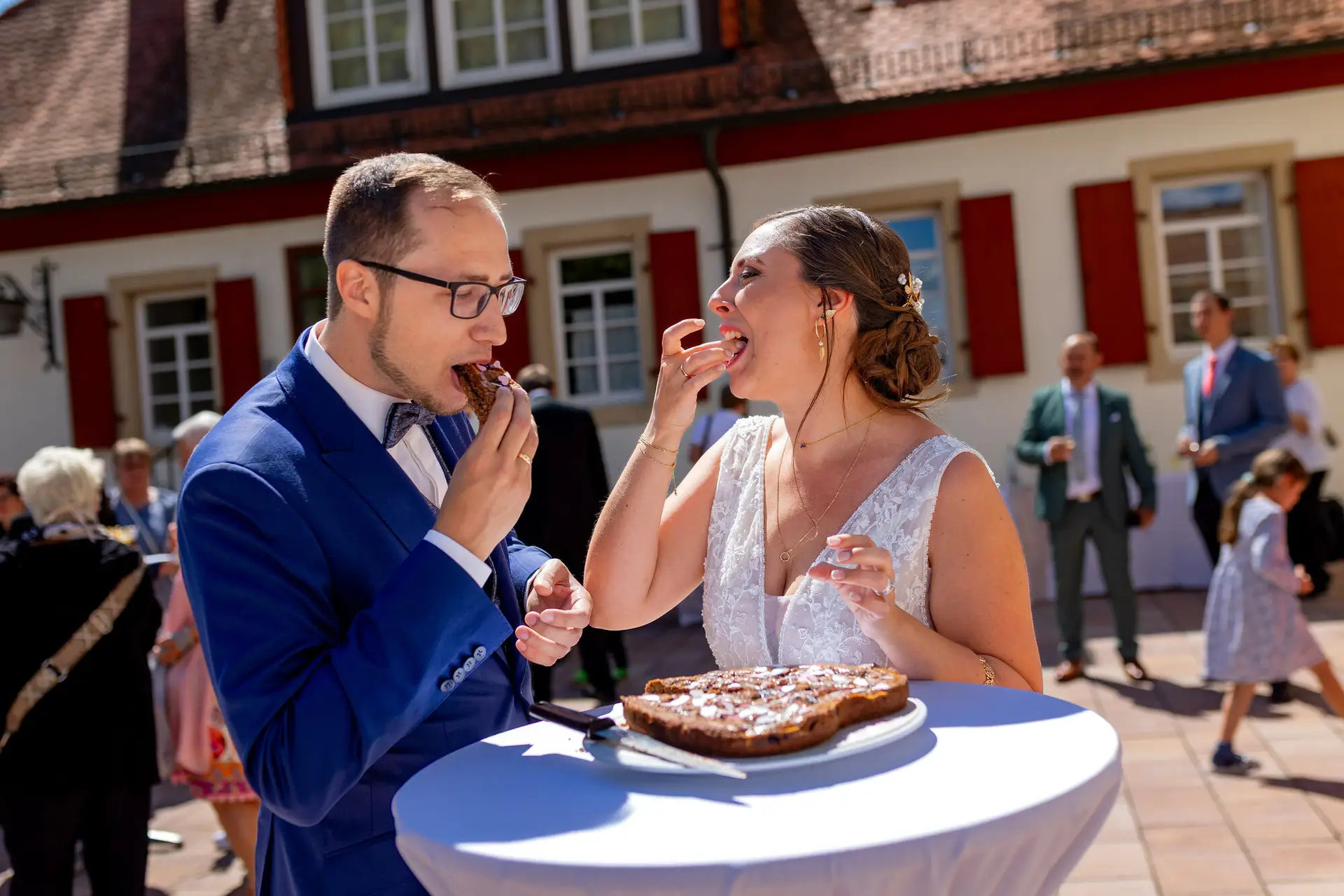 Brautpaar teilt gemeinsam ein Stück Hochzeitstorte vor der Kirche in Mutterstadt