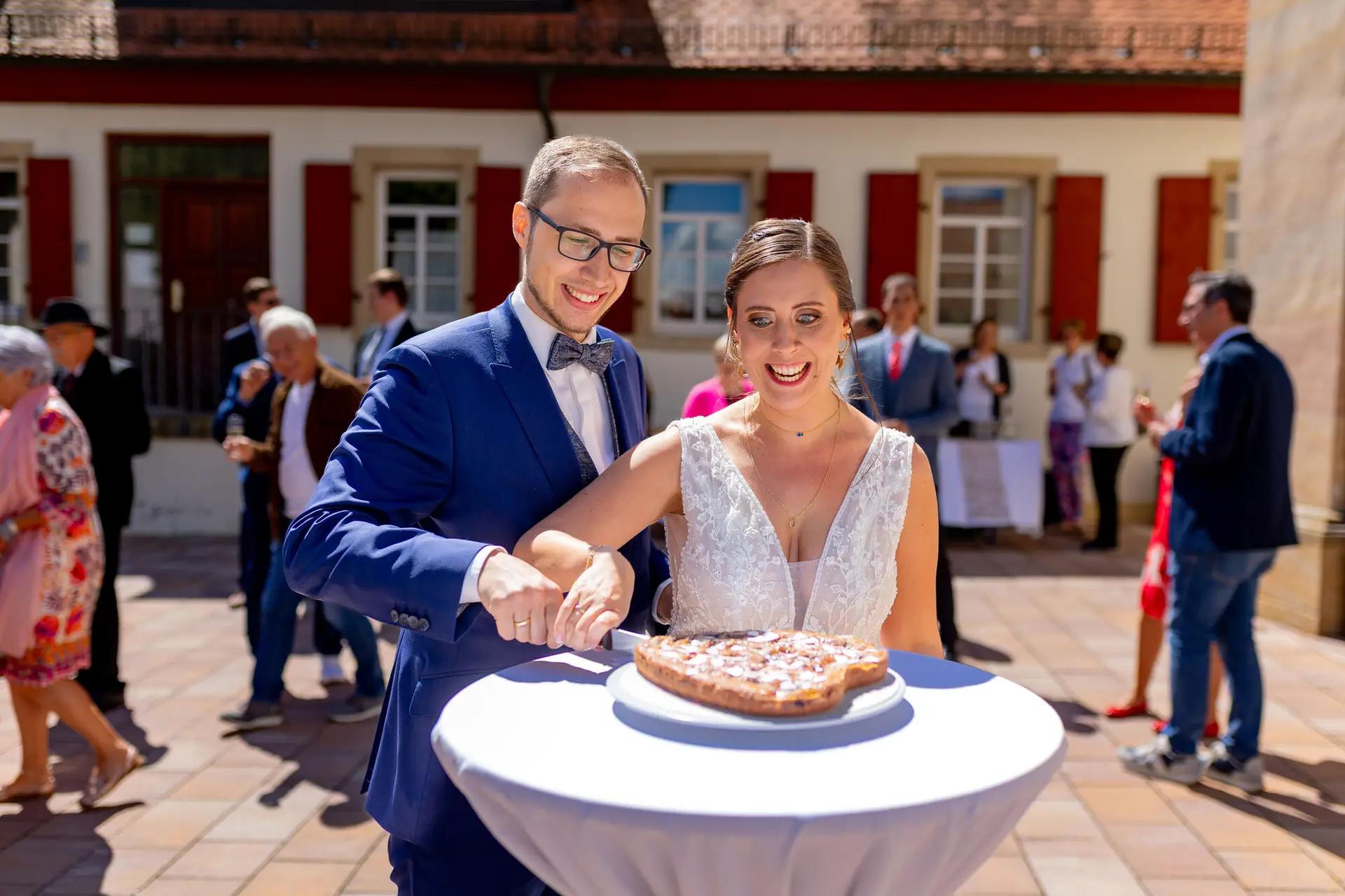 Brautpaar schneidet gemeinsam die Hochzeitstorte vor der Kirche in Mutterstadt an