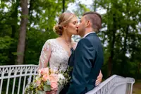 Hochzeitsfotograf im Schlossgarten Worms: Brautpaar umarmt sich romantisch auf einer weißen Brücke im Grünen.