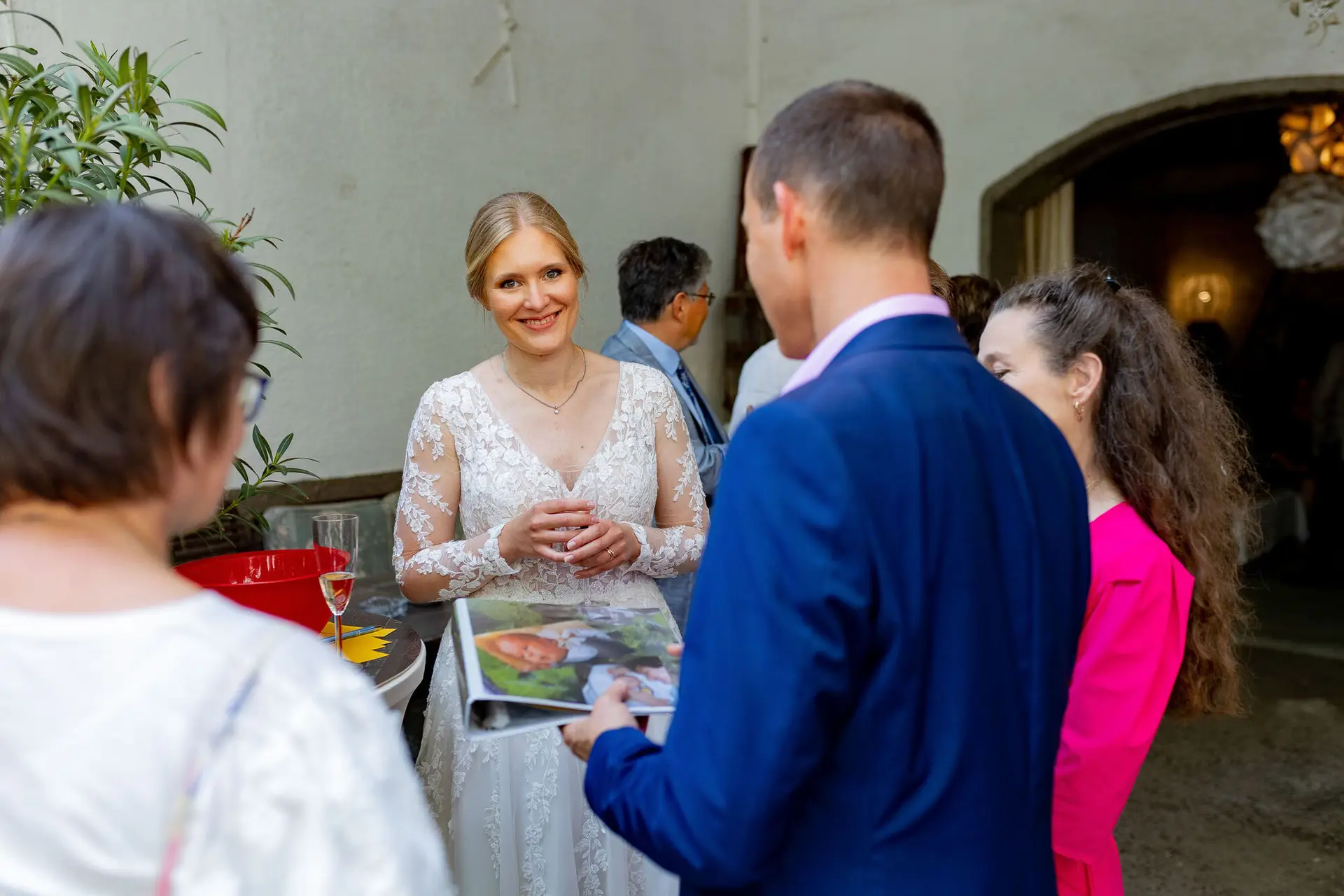 Braut im weißen Spitzenkleid im Gespräch mit Gästen im Innenhof des Dach der Welten