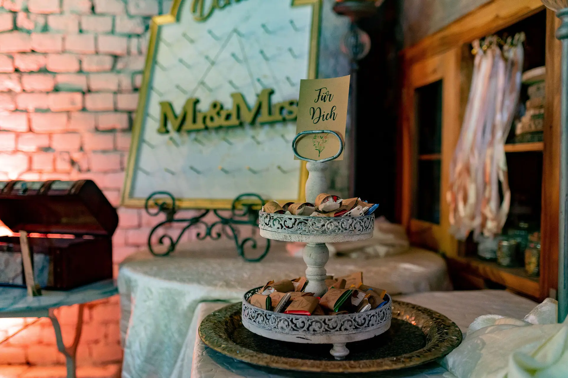 Etagere mit verpackten Gastgeschenken und "Für Dich"-Schild, "Mr & Mrs"-Schild an der Steinwand im Hintergrund