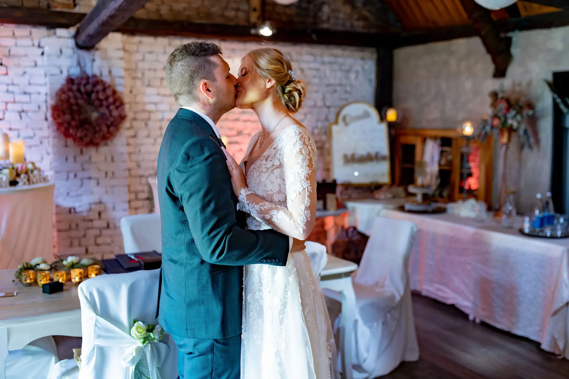 Brautpaar küsst sich innig im Steingemäuer-Innenraum mit Herz-Dekoration an der Wand