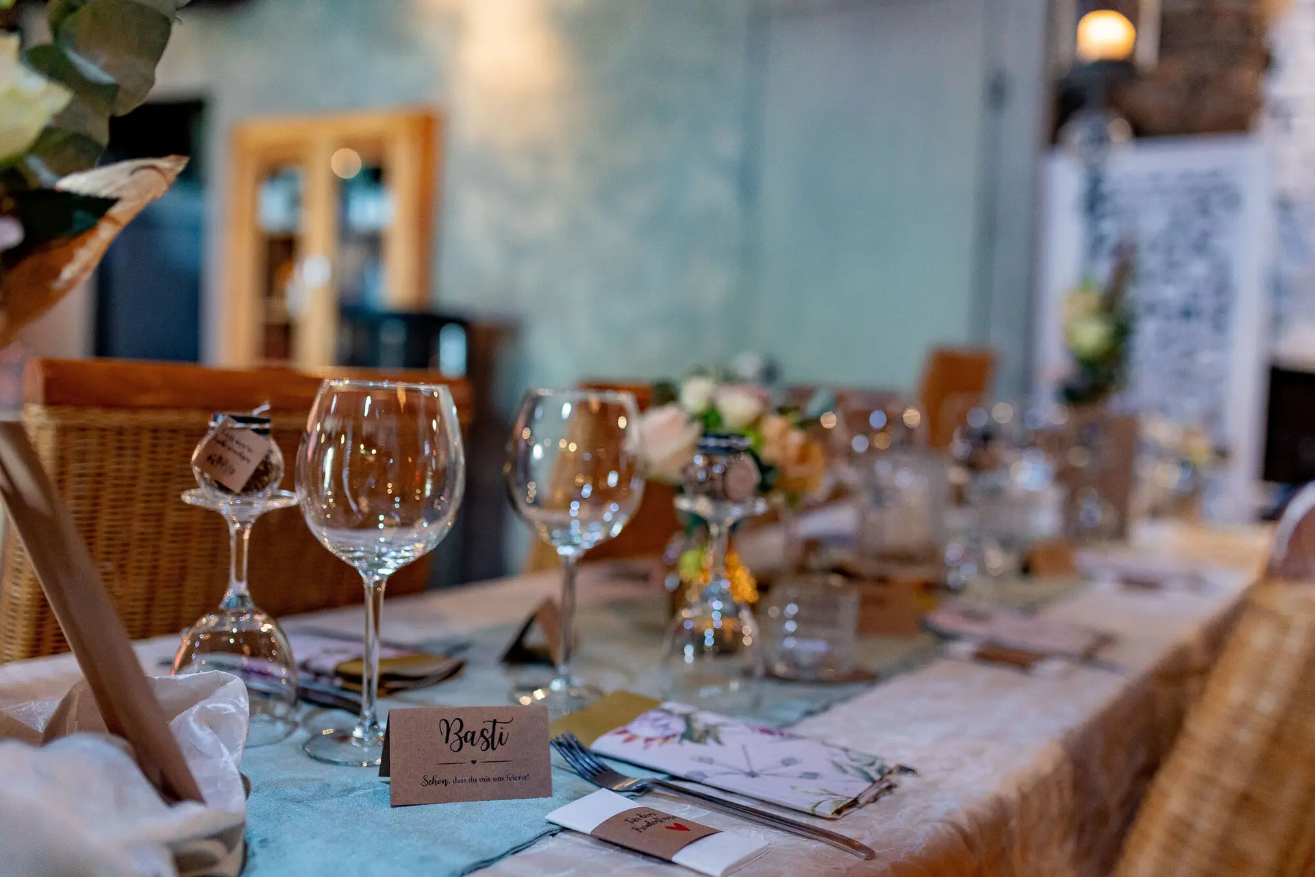 Gedeckter Tisch im Dach der Welten mit Weingläsern, Blumenarrangement und persönlichen Tischkarten in warmem Ambiente